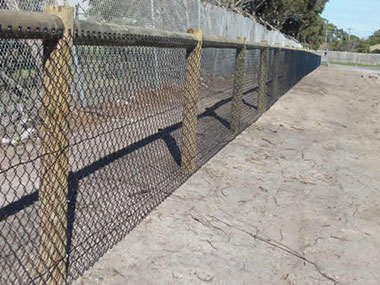Chain mesh fence with razor wire and barbed wire.